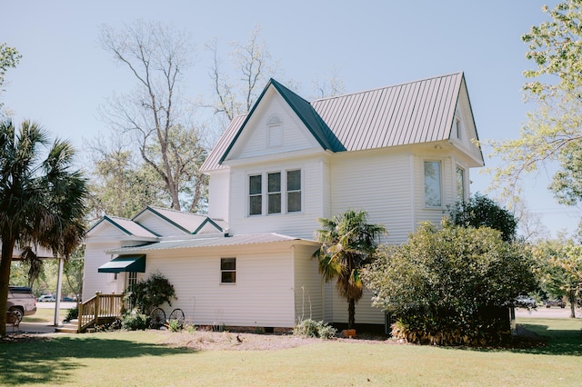 view of property exterior featuring metal roof and a lawn