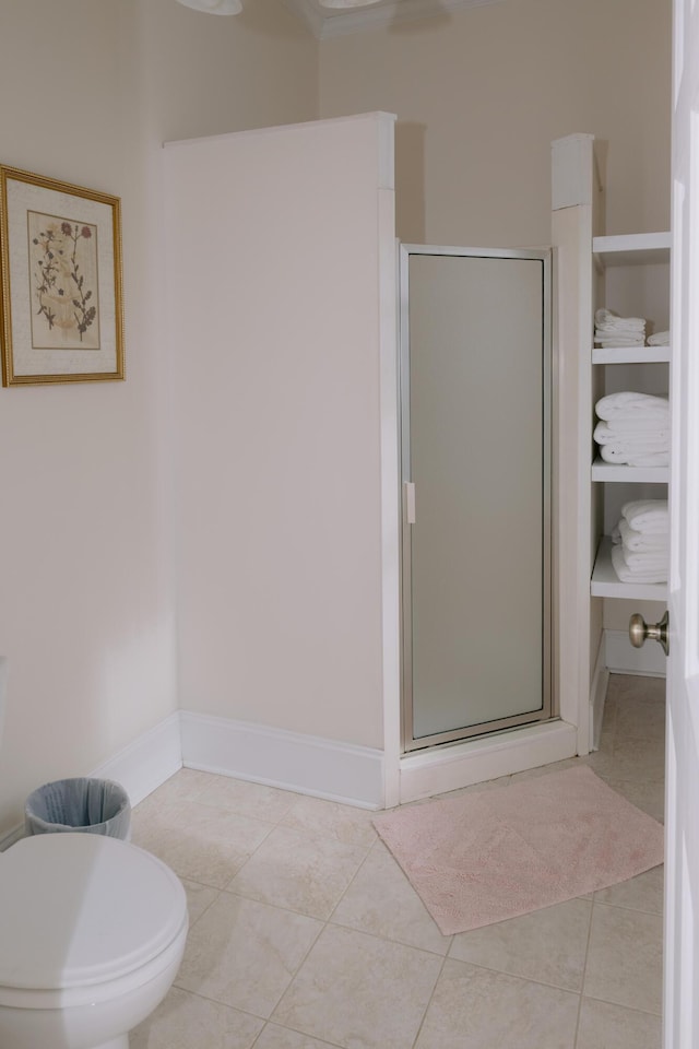 bathroom with toilet, a stall shower, tile patterned flooring, and baseboards