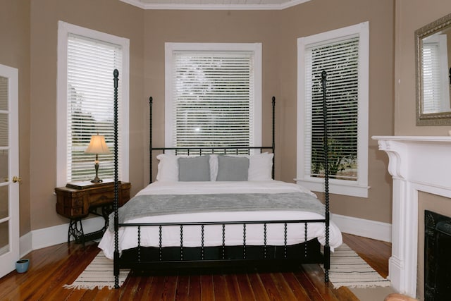 bedroom with hardwood / wood-style floors, ornamental molding, and baseboards