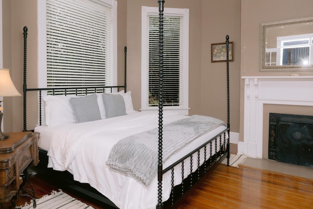 bedroom featuring a fireplace, wood finished floors, and baseboards