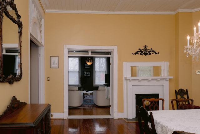 interior space with hardwood / wood-style flooring, a chandelier, baseboards, ornamental molding, and a fireplace