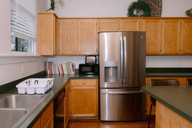 kitchen with black appliances, a sink, dark countertops, and dark wood finished floors