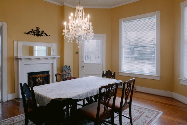 dining area featuring wood finished floors, plenty of natural light, crown molding, and a notable chandelier