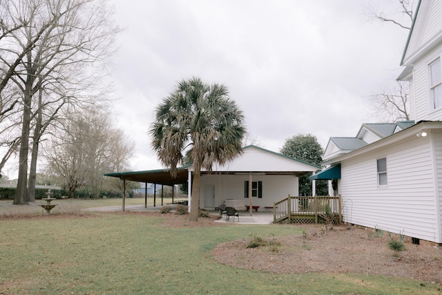 back of house featuring a lawn, a wooden deck, and an attached carport