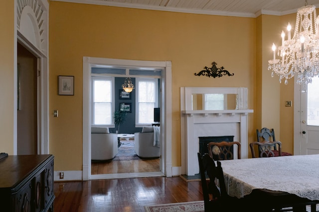 dining space with a chandelier, crown molding, dark wood-style flooring, and a fireplace