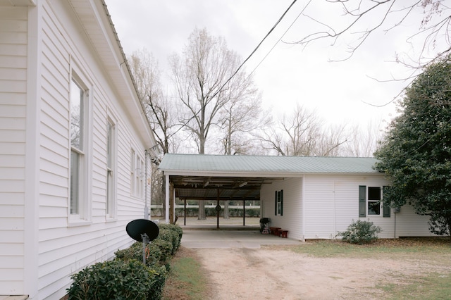 view of side of property featuring dirt driveway and an attached carport
