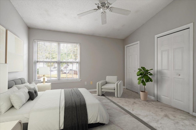 bedroom featuring a textured ceiling, light carpet, ceiling fan, and vaulted ceiling