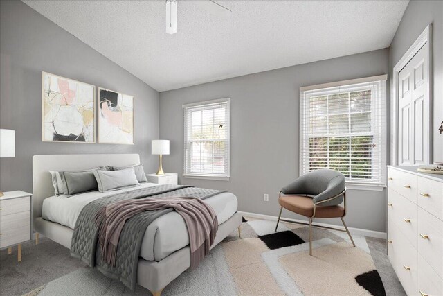 bedroom with a textured ceiling, light carpet, ceiling fan, and vaulted ceiling