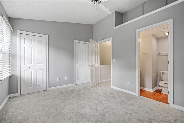 unfurnished bedroom with light carpet, ensuite bathroom, ceiling fan, a textured ceiling, and lofted ceiling