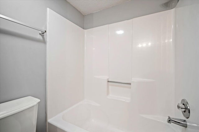 bathroom featuring toilet, washtub / shower combination, and a textured ceiling