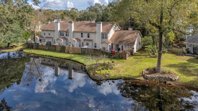 back of house featuring a water view and a lawn