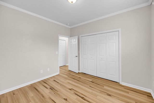 unfurnished bedroom featuring wood finished floors, crown molding, baseboards, and a closet