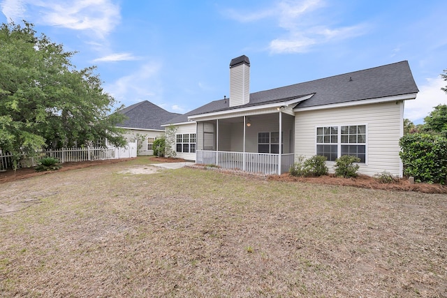 back of house featuring a chimney, roof with shingles, a patio area, and a sunroom