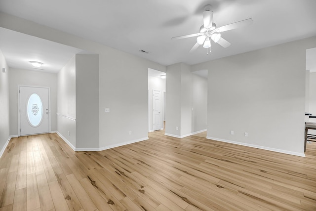 unfurnished living room featuring ceiling fan, light wood finished floors, and baseboards