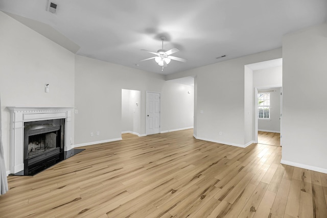 unfurnished living room with ceiling fan, light wood-style floors, baseboards, and a fireplace