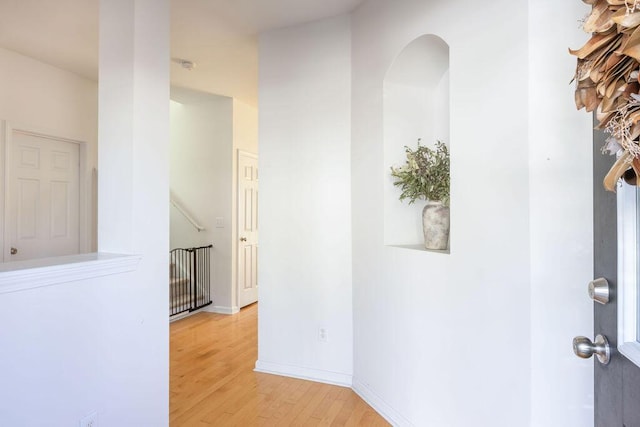 hall with light wood-style flooring and baseboards