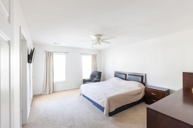 bedroom with ceiling fan, baseboards, and light colored carpet