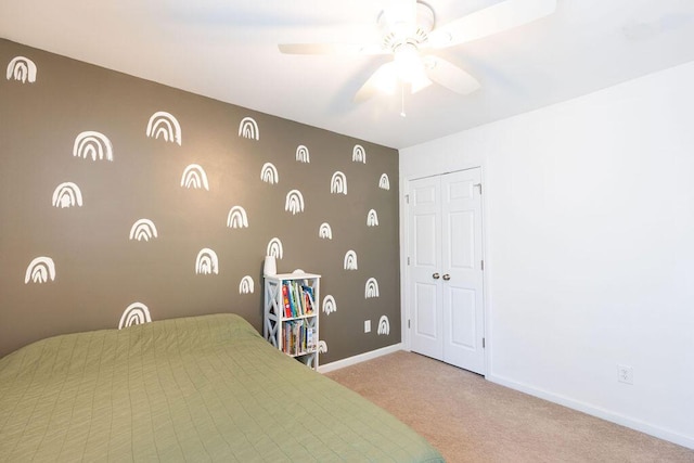 bedroom with a closet, light colored carpet, ceiling fan, and baseboards