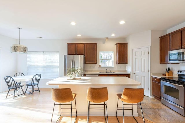 kitchen with stainless steel appliances, light countertops, a sink, and a breakfast bar area