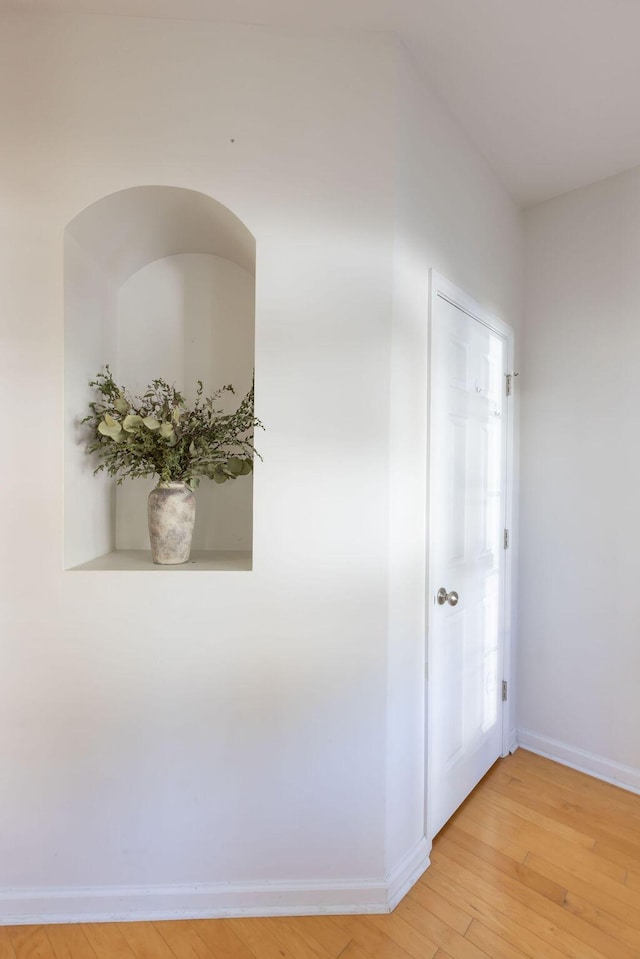 hallway featuring light wood finished floors and baseboards