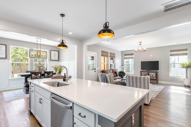 kitchen featuring stainless steel dishwasher, sink, light hardwood / wood-style floors, and a center island with sink