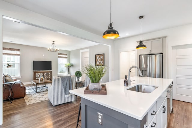 kitchen featuring pendant lighting, stainless steel fridge with ice dispenser, an island with sink, and dark hardwood / wood-style flooring