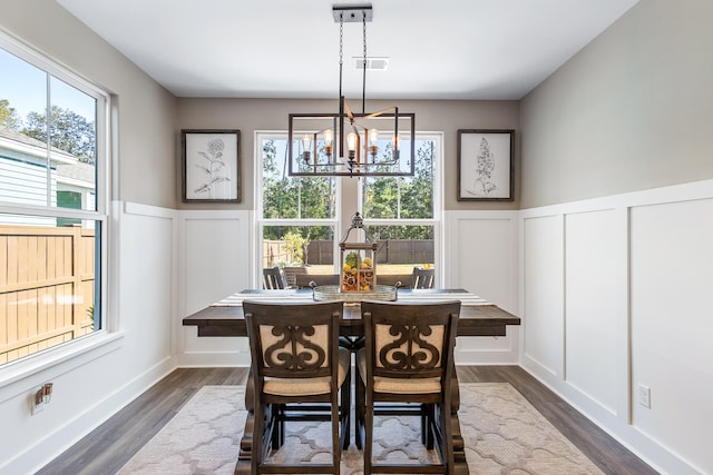 dining area featuring a notable chandelier, a healthy amount of sunlight, and dark wood-type flooring