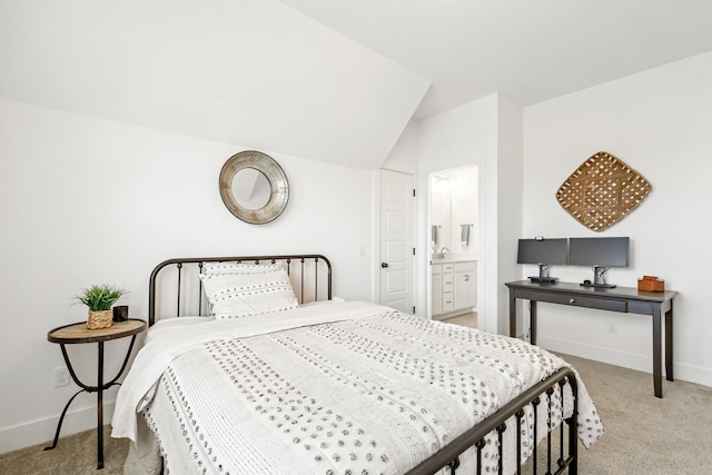 bedroom featuring lofted ceiling, light colored carpet, and ensuite bath