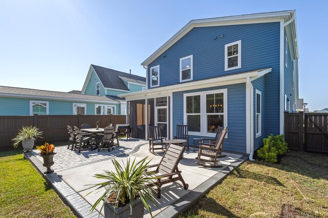 rear view of property featuring a patio, a yard, and a sunroom