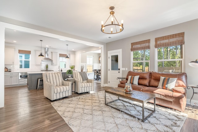 living room featuring a notable chandelier, a healthy amount of sunlight, and wood-type flooring