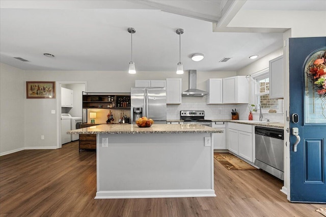 kitchen with appliances with stainless steel finishes, a center island, white cabinetry, and wall chimney range hood