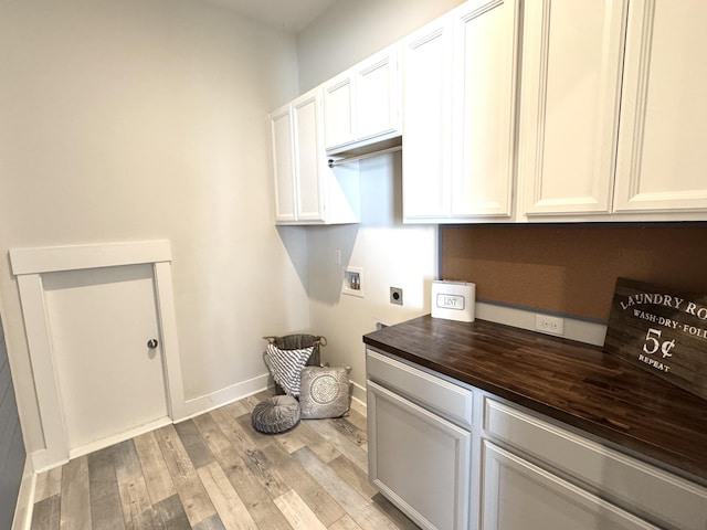 washroom with cabinet space, baseboards, light wood-style flooring, hookup for a washing machine, and hookup for an electric dryer