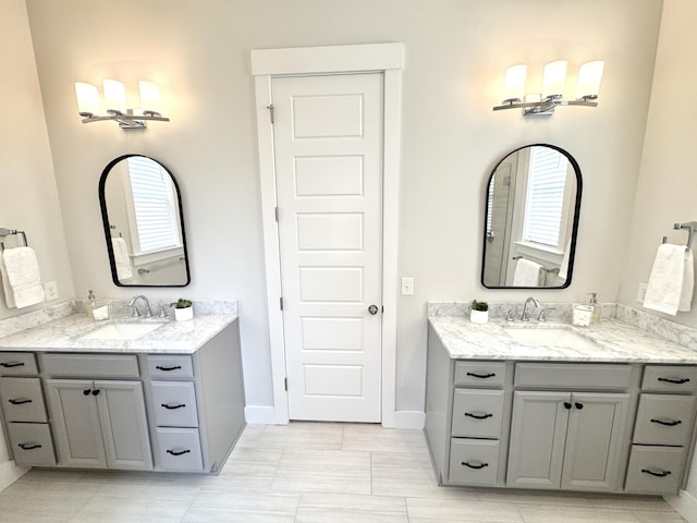 full bath featuring two vanities, a sink, and baseboards