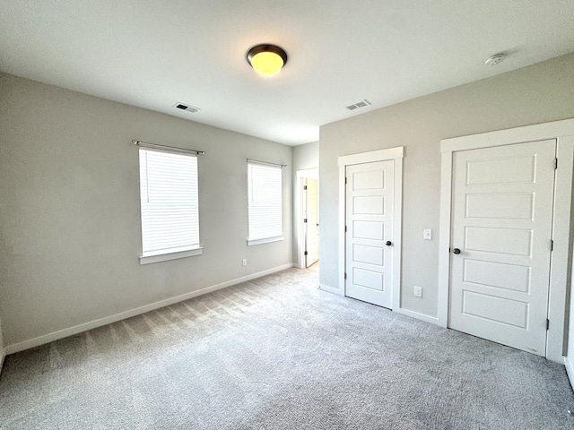 unfurnished bedroom with carpet, visible vents, and baseboards