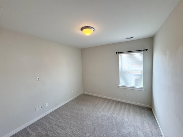 empty room with carpet flooring, visible vents, and baseboards