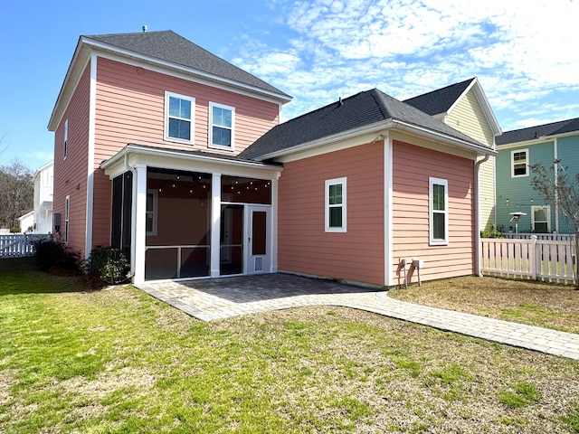 rear view of house with a patio, a shingled roof, fence, a sunroom, and a lawn