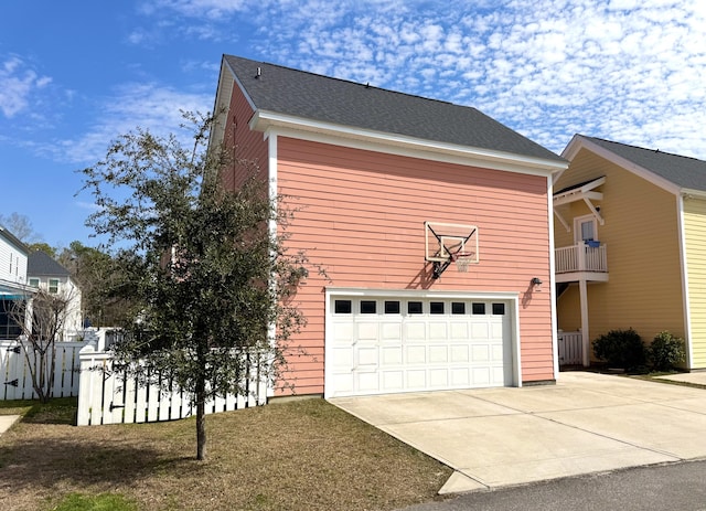 exterior space with concrete driveway, fence, a balcony, and an attached garage