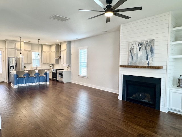 unfurnished living room featuring dark wood-style flooring, visible vents, ceiling fan, and a fireplace