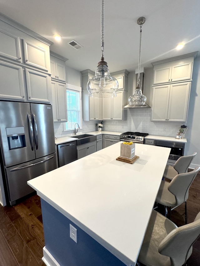 kitchen featuring visible vents, decorative backsplash, wall chimney exhaust hood, stainless steel appliances, and a sink