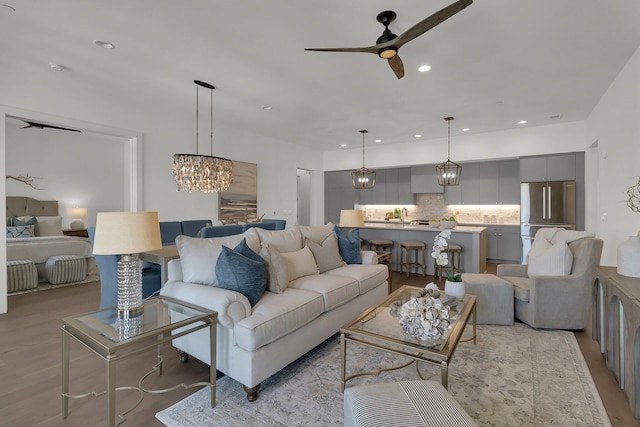 living room with ceiling fan with notable chandelier and light wood-type flooring