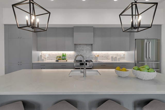 kitchen with appliances with stainless steel finishes, a kitchen breakfast bar, tasteful backsplash, and hanging light fixtures