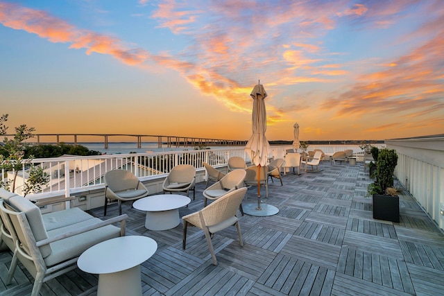 deck at dusk featuring a water view