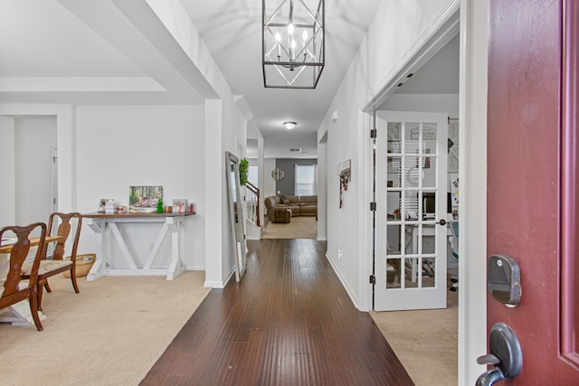 carpeted entrance foyer featuring an inviting chandelier