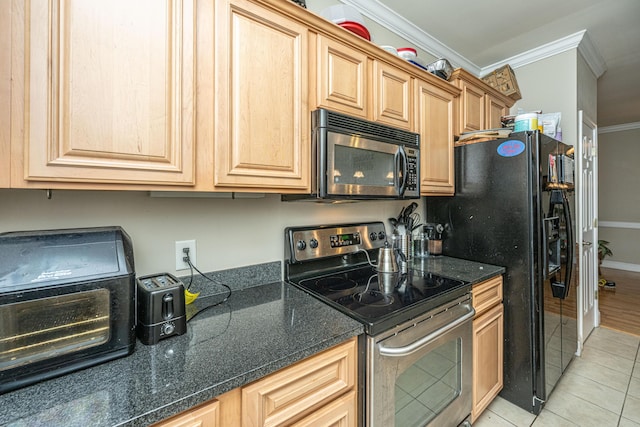 kitchen with dark stone counters, crown molding, light tile patterned flooring, and stainless steel appliances