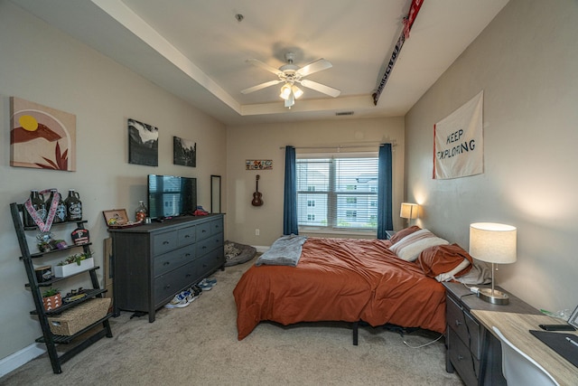 bedroom with light carpet, a raised ceiling, and ceiling fan