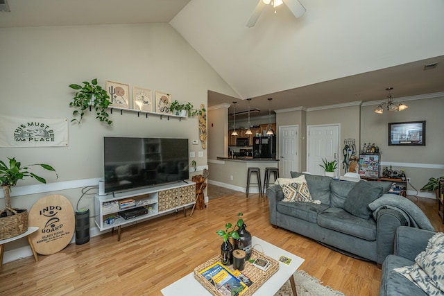 living room with vaulted ceiling, wood-type flooring, ceiling fan with notable chandelier, and ornamental molding