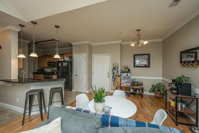 dining area featuring light hardwood / wood-style flooring, an inviting chandelier, ornamental molding, and sink