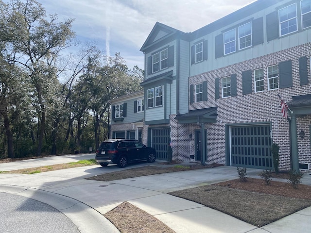 townhome / multi-family property featuring driveway, an attached garage, and brick siding