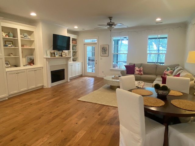 living area with ceiling fan, recessed lighting, a fireplace, and light wood-style floors