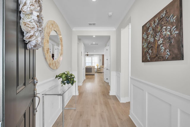 hall with light hardwood / wood-style flooring and ornamental molding